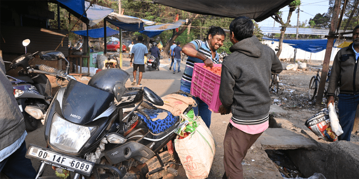 Two men handling a crate of produce at a market.