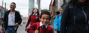 A group of happy people walking down a sidewalk with smiling child front and center.