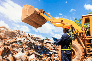 city employee working at landfill next to yellow wheel loader truck