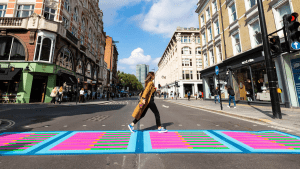 Woman in London walks in colorfully painted crosswalk.