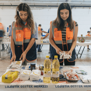 Two female volunteers prep dry goods packages on a table for Istanbul residents as part of the Pay It Forward program.