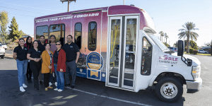 Staff of the Mobile Career Unit pose for a group photo in front of a Mobile Career Unit bus.