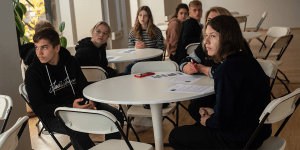 Students sitting at round tables at attention.