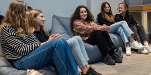 Students sitting in bean bag chairs, smiling.