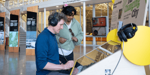 Two people listening to an audio file at an exhibit.