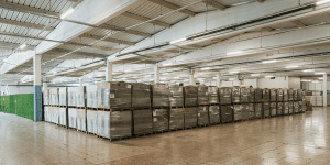 A large warehouse with numerous pallets of goods wrapped in plastic, neatly stacked and organized.