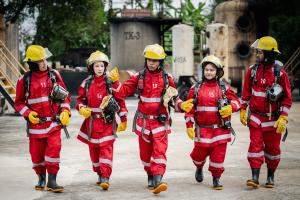 An image of four firefighters wearing bright red uniforms and yellow helmets.