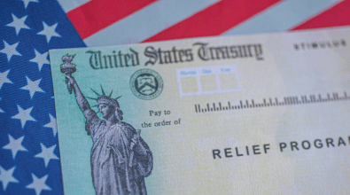 A photo of a United States Treasury "Relief Program" check resting on an American Flag.