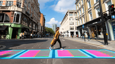Woman in London walks in colorfully painted crosswalk.