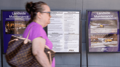 A woman walking by a poster that reads "landslide maintenance"