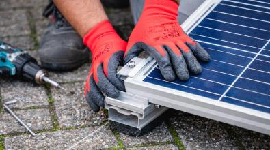Two hands working to assemble a solar panel.