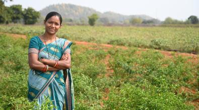 Woman standing in front of field with her arms folded.