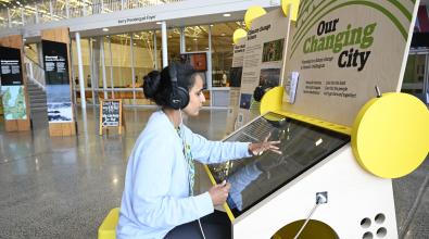 A woman with headphones listening to an exhibit.