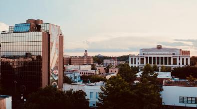 Evening in La Fayette, Louisianna. A building with reflective windows is in the foreground, showing the cityscape behind the camera.