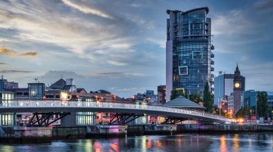 Sunset over Belfast with colorful twilight sky above the Lagan Weir pedestrian and cycle bridge spanning the Lagan River in downtown Belfast.